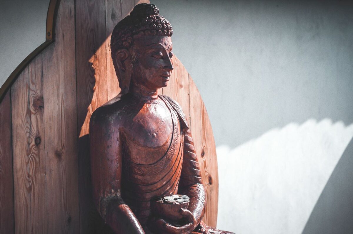 Arassoc A serene wooden Buddha sculpture illuminated by gentle sunlight, evoking peace and spirituality.